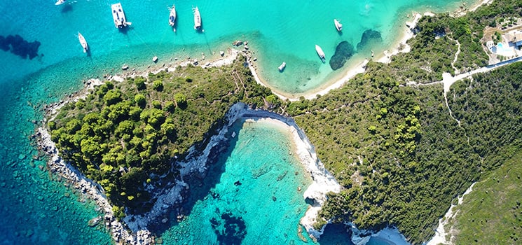 This aerial image showcases a picturesque Caribbean island. Dotted with sailboats, the brilliant turquoise waters encircle a lush, verdant landmass. The dramatic contrast of colors creates a visually stunning scene.