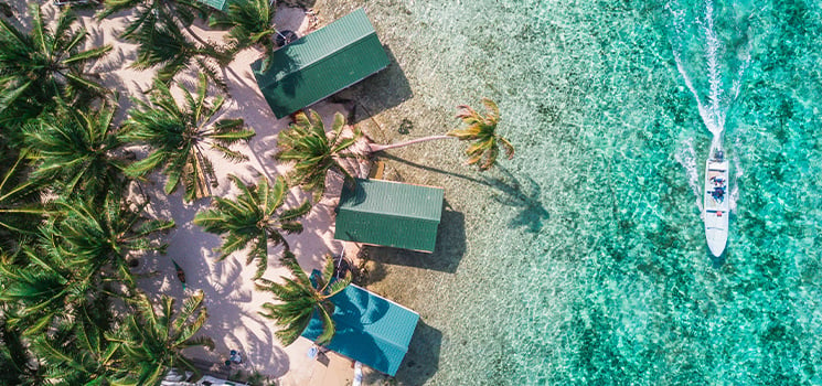 Aerial drone view of Tobacco Caye small Caribbean island with palm trees and bungalows in the Belize Barrier Reef