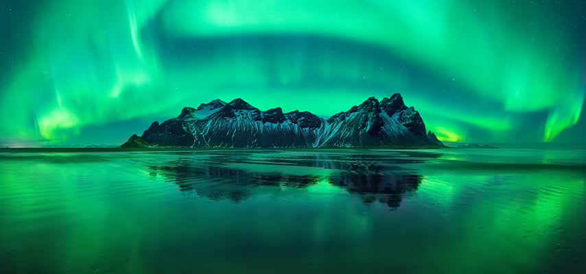 Aurora reflections on Stokksnes black beach with Vestrahorn mountains in center, Iceland