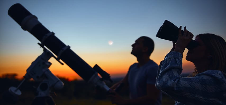 Couple stargazing together with a astronomical telescope