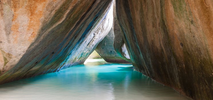 This hidden cave in the British Virgin Islands features striking turquoise waters flowing between rugged, ancient rock walls. The dramatic, cathedral-like space is an awe-inspiring natural wonder.