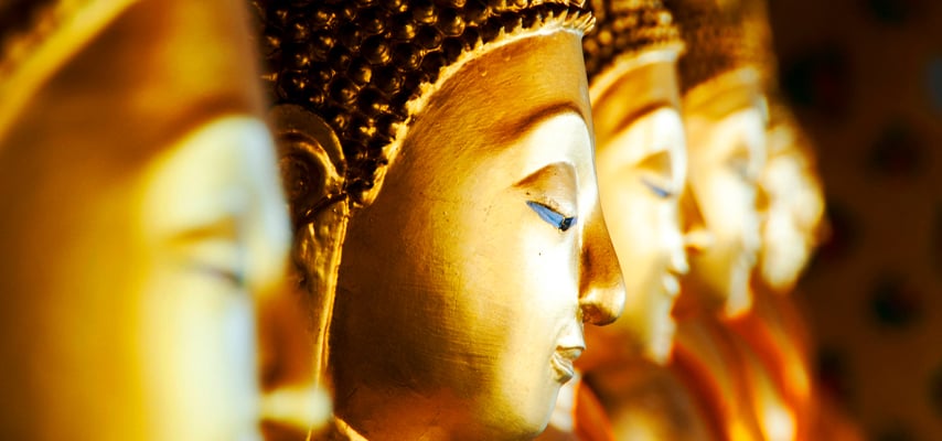 Close-up of golden Buddha statues in a row with serene expressions and ornate details.