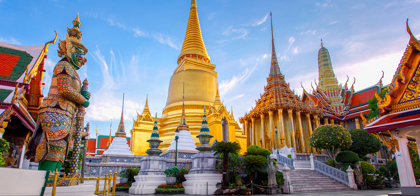 Grand Palace complex in Bangkok with golden spires, colorful guardian statues, and ornate architecture.