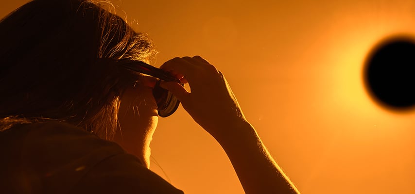 Woman looking at solar eclipse through solar glasses.