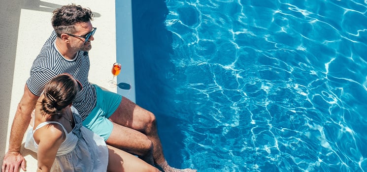 Young couple sitting by the pool on the empty deck of a cruise liner