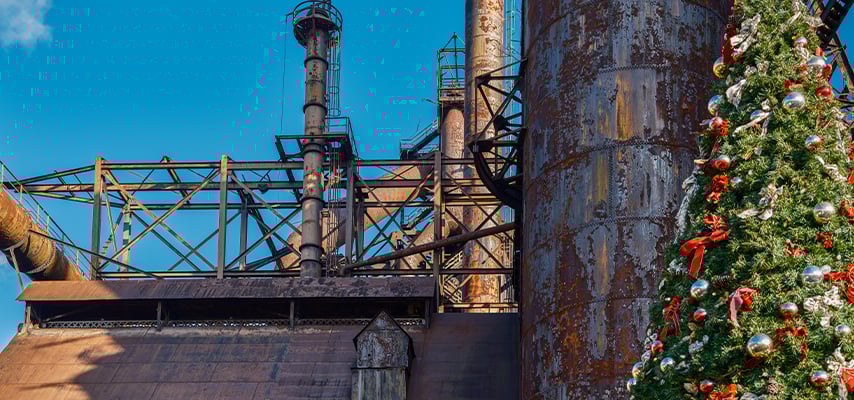 Industrial Christmas tree with red decorations displayed near rusty steel structures and smokestacks in Bethlehem, PA.
