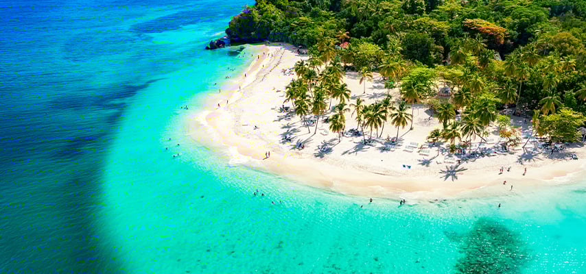 Aerial view of white sand beach with palm trees surrounded by brilliant turquoise water