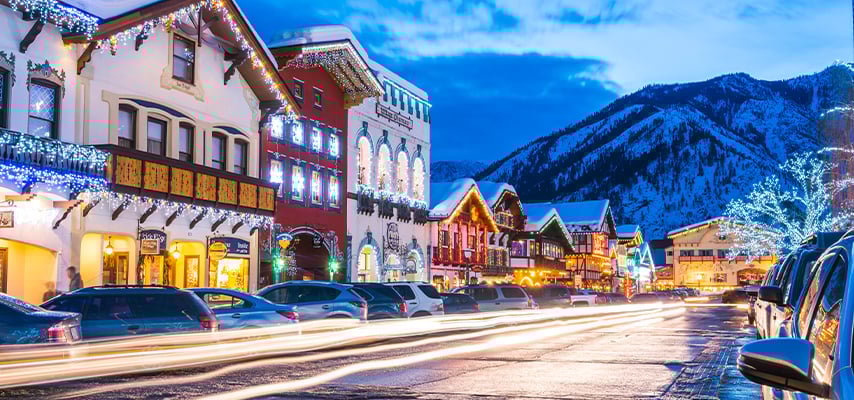 Colorful historic buildings decorated with Christmas lights line Leavenworth Washington street at dusk.