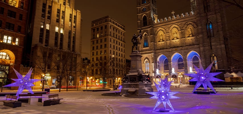 Purple illuminated star decorations and historic buildings in Montreal.