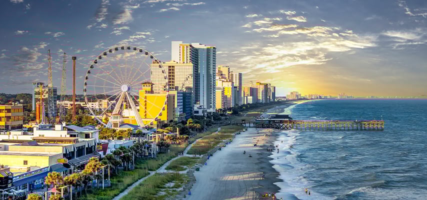 Myrtle Beach South Carolina skyline at sunset with ferris wheel, high-rises, and beach