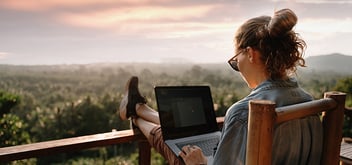  Young girl working on a laptop at sunset on the top of the mountain