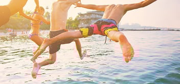 Group of happy crazy people having fun jumping in the sea water from boat.
