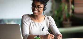woman in earphones studying taking notes