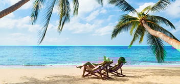 couple sitting and relaxing on a beach with palm trees