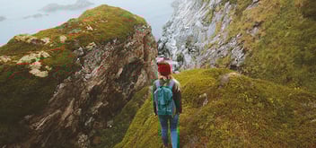 person traveling in the mountains with backpack and greenery