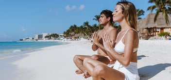 Young couple relaxing in meditation on a Caribbean beach.