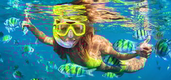 woman snorkeling underwater with colorful fish 