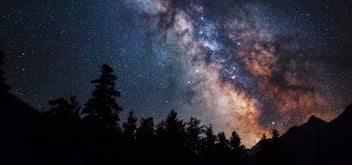 Astrophotography of Milky Way galaxy with the silhouette of mountains trees at the bottom