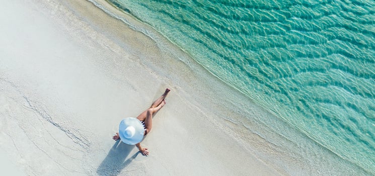 Caribbean beach scene depicting a lone figure lying on the soft, white sand, gazing out at the captivating turquoise waters.